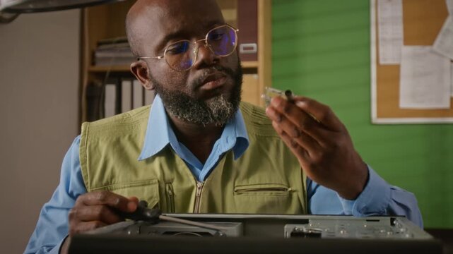 African American man unscrewing computer case, removing and examining electronic component. Video is suitable for IT support services and hardware repair advertisements