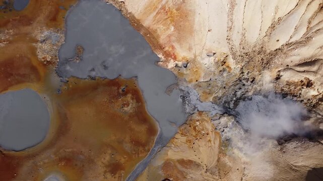 Aerial view of Landmannalaugar geothermal landscape with colorful mineral deposits, steaming vents, and grey water pools in Rangarthing ytra, Iceland.