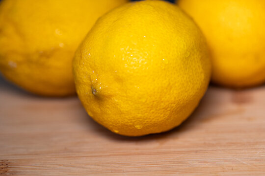 Close-up of three lemons on a cutting board, subtropical fruit. Contains vitamin C, freshness, citrus fruit, healthy eating.