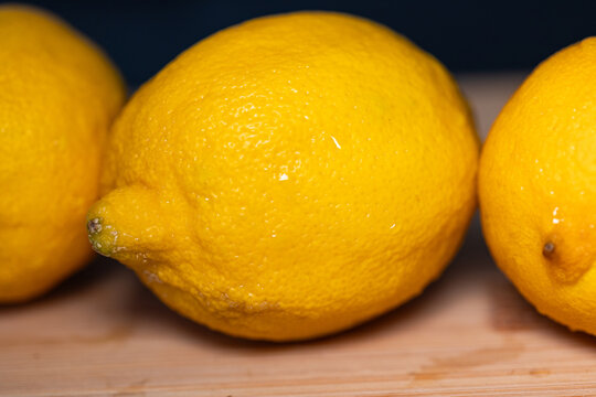 Close-up of three lemons on a cutting board, subtropical fruit. Contains vitamin C, freshness, citrus fruit, healthy eating.