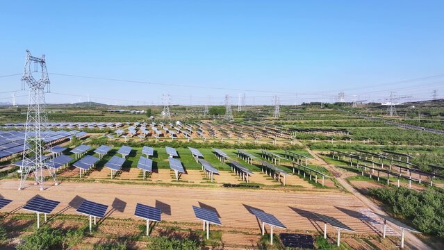 Large scale photovoltaic power station array with transmission towers under clear blue sky