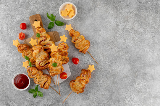 Puff pastry Christmas tree buns with cheese and ham on a board. Christmas and New Year appetizer. Top view, copy space.