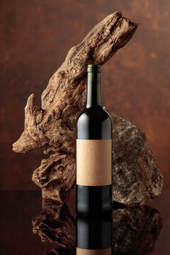 Bottle of red wine with old driftwood and a piece of granite rock.