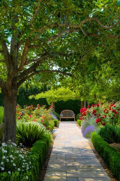 Serene stone pathway winding through a lush green garden with blooming red roses and a wooden bench