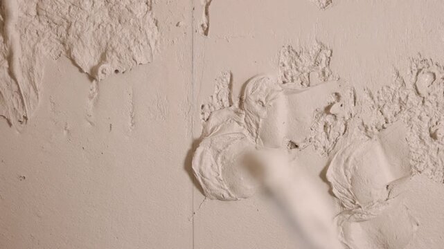 Construction work, Construction site, Skilled labor. Close detail plaster finishing as hands guide long straightedge across fresh wall plaster.