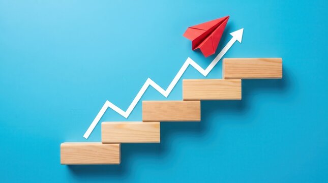 Red paper airplane flying over rising wooden block stairs with business
