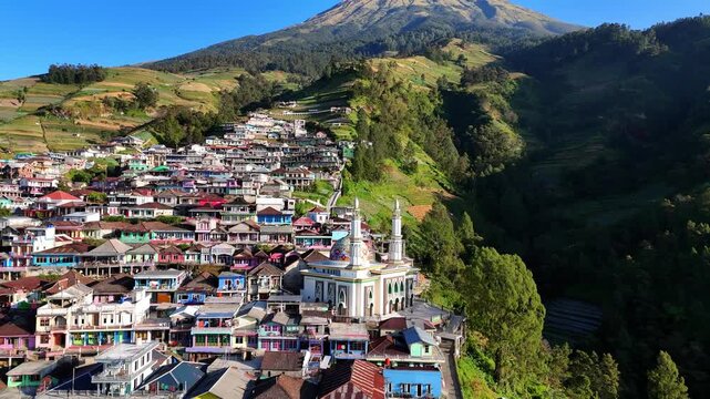 Aerial view of Nepal Van Java with colorful houses built on the mountain slopes and a prominent mosque in Kecamatan Kaliangkrik, Jawa Tengah, Indonesia.