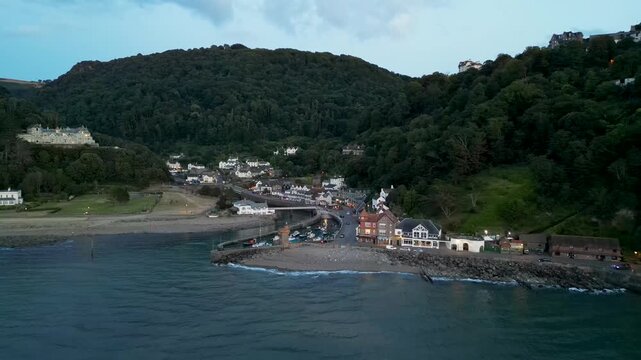 Aerial view of the coastal village of Lynmouth with its harbor, historic buildings, and surrounding green hills along the coast in Lynmouth, England, United Kingdom.