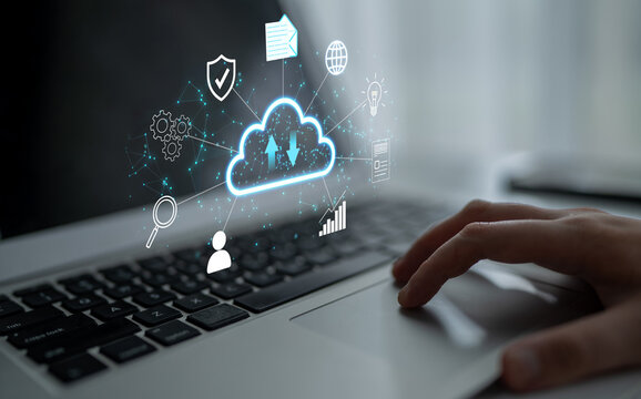 Concept of cloud computing with various digital icons hovering above a laptop keyboard, representing data security, file sharing, and remote accessibility. Entropy.
