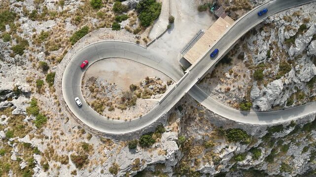 Aerial top down view of cars driving along famous Nus de Sa Calobra tie knot loop mountain road in Mallorca Spain