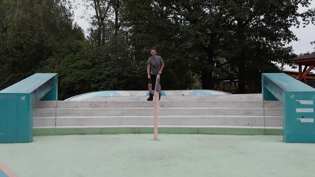 Slow motion of a mature man riding backwards down concrete stairs on aggressive inline skates at a skatepark