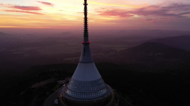 Aerial view of Jested Tower atop the mountain at sunset with a vibrant sky and surrounding hills in Liberec, Liberecky kraj, Czechia.