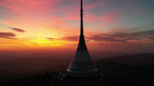 Aerial view of Jested Tower illuminated by the warm glow of a vibrant sunset, showcasing the iconic architecture of the transmitter in Liberec, Liberecky kraj, Czechia.