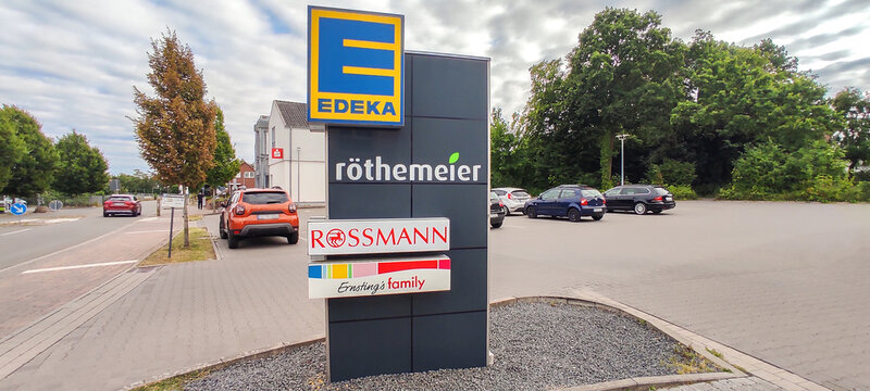Germany, Minden - July 5, 2025: Retail store sign pillar with Edeka, Rossmann, Ernsting's family and R&ouml;themeier logos at shopping park entrance in Germany
