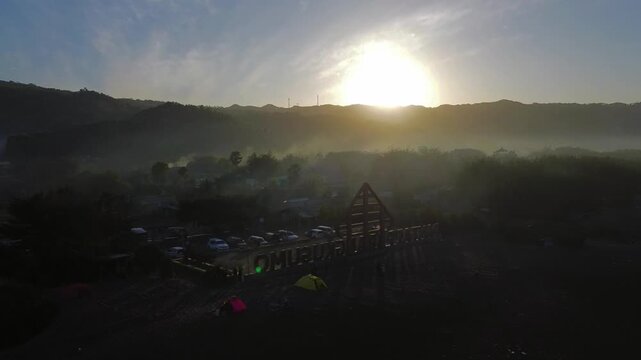 Aerial view of Pantai Parangkusumo sign with tents on the beach at sunrise in Kecamatan Kretek, Daerah Istimewa Yogya, Indonesia.