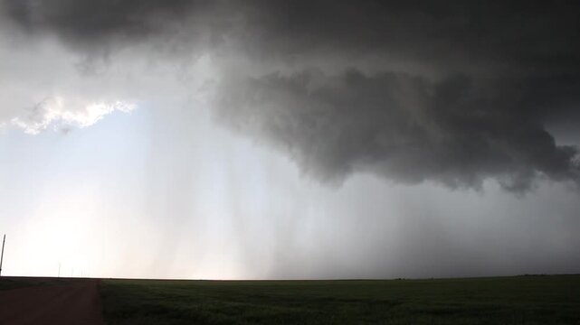 Rain falls from a small storm cloud over the prairie. Time lapse.