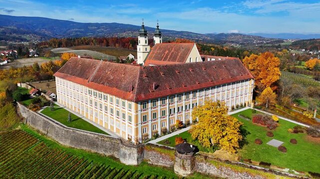 Aerial view of the historic Schloss Stainz monastery surrounded by autumn vineyards and colorful foliage in Stainz, Styria, Austria.