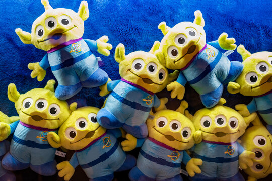 Bangkok, Thailand - August 3, 2026 : Three cute green alien plush dolls with three eyes from toy story movie character sitting on wooden shelf in a store.