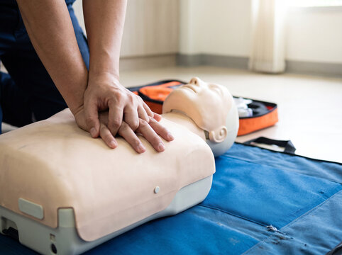 Hands Performing Chest Compressions on CPR Training Manikin During First Aid Class in Bright Practice Room