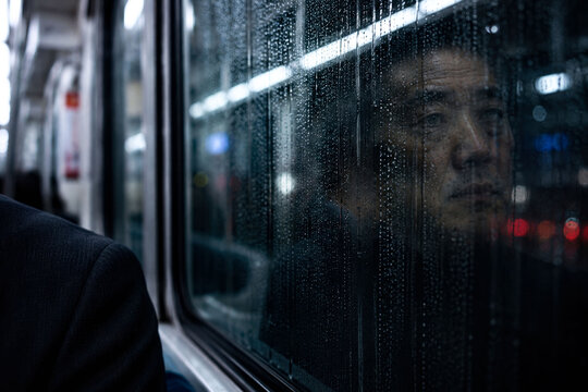 Elsewhere &mdash; Reflection of a silent commuter fading into a rain covered subway window