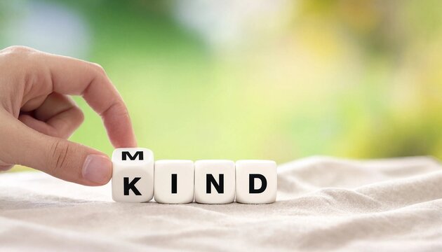 Kind mind concept. Finger flips letter at wooden cube changing the word mind to kind. 
