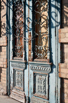 Vintage double wooden door with ornate ironwork chained and weathered facade