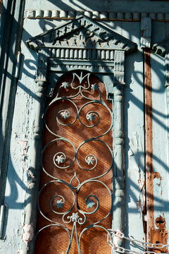 Close-up of ornate vintage door panel with peeling paint and ironwork