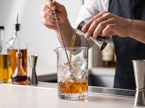 Bartender pouring liquor into a glass with ice and stirring a cocktail