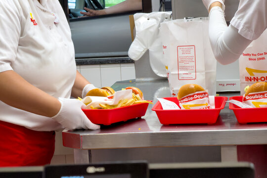 Fast food kitchen workers working with Trays of burgers and fries ready to be picked up by the customers at a local In n Out burger restaurant