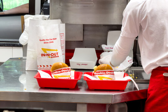 Fast food kitchen workers working with Trays of burgers and fries ready to be picked up by the customers at a local In n Out burger restaurant
