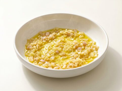 Finely diced onions sautОed in olive oil in a white bowl