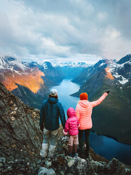 Family travel parents and child on hiking vacations outdoor together in Norway - father, mother and daughter enjoying lake and mountains aerial view from mountain top healthy lifestyle explore Romsdal