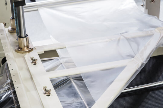 Automatic conveyor line for packaging food products into transparent, disposable plastic vacuum containers or boxes. tech industrial technology background