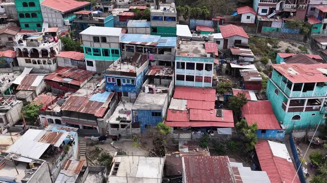 Aerial view of dense urban rooftops with colorful metal sheets and concrete structures in Santiago Atitlan, Solola Department, Guatemala.