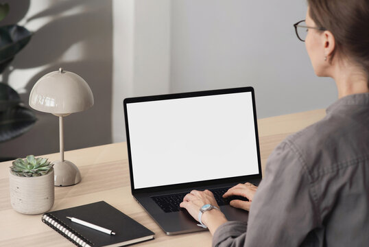 Young woman using laptop with blank empty mockup screen, female hands typing on computer keyboard closeup. Working or studying from home office, freelance, shopping online, web site design concept.