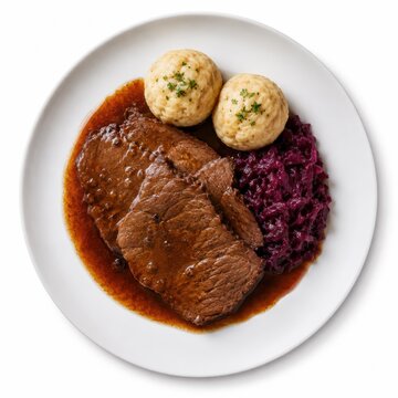 Sauerbraten mit dunkler Sauce, Rotkohl und Kartoffelkn&ouml;deln auf wei&szlig;em Teller, freigestellt in Top-View. Klassisches deutsches Festtagsgericht f&uuml;r Gastronomie und Food-Projekte.