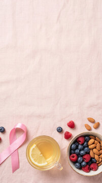 Breast cancer awareness ribbon with lemon tea, berries and almonds for healthy prevention lifestyle