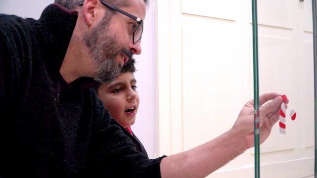 Boy enjoying Christmas decorating with his father at home
