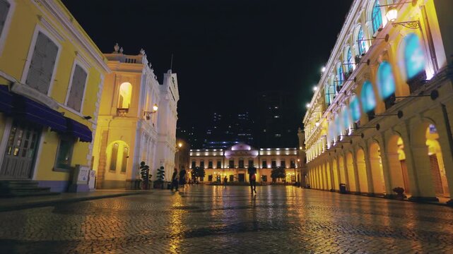Slow motion of Macau Senado Square at night with illuminated historic buildings and cobblestone ground