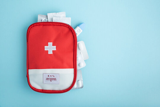 Red first aid kit with medical supplies on a light blue background