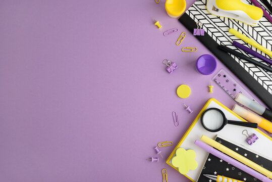 Stationery supplies arranged on a purple background, top view, flat lay