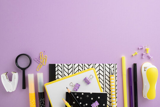 Stationery flat lay with notebooks, pens, clips, magnifying glass, stapler