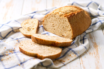 Naklejka premium loaf of artisan bread or traditional wheat rustic bread on white kitchen table.