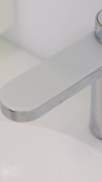 Male hand pressing electronic faucet button to turn off running water after washing hands in modern clinic maintaining clean and efficient workplace close up video