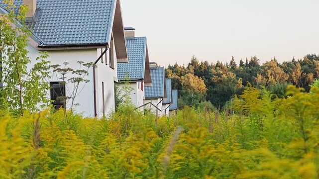 An abandoned unfinished suburban house cottage overgrown with wild grass, concept of financial crisis, housing market bubble burst, developer bankruptcy and frozen construction project investment