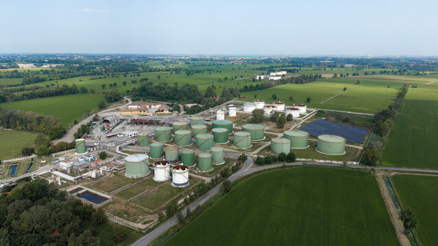 Aerial view of the Sigemi S.r.l. industrial facility featuring numerous green storage tanks surrounded by lush green fields and rural landscape in Lacchiarella, Lombardia, Italy.