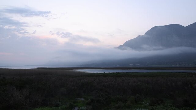 country road with delicate fog hovering below Klein Mountains and lagoon and country road, Stanford, South Africa