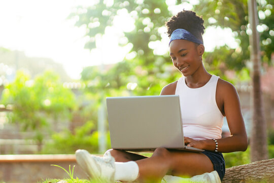 African woman studying on laptop outdoors enjoying nature