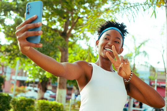 African woman taking self portrait making peace gesture