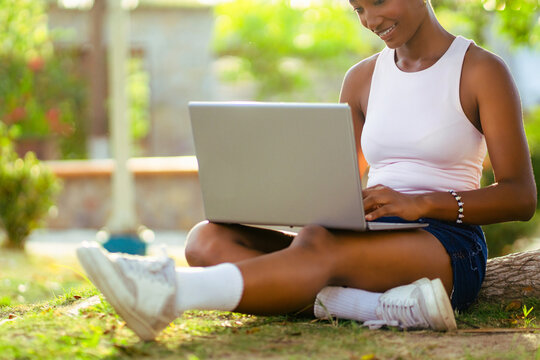 African woman connecting online using laptop outdoors